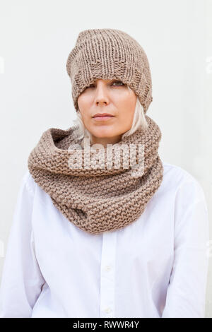 Jolie jeune femme au chapeau tricoté marron chaud et snood. Banque D'Images