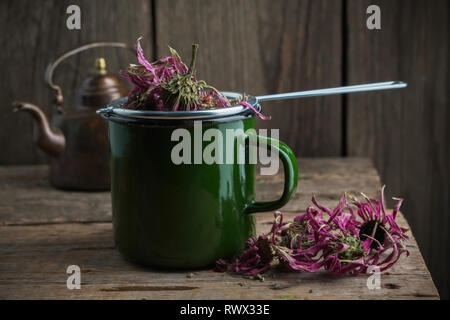 Tasse émaillée d'échinacée sain avec plateau à thé, d'herbes sèches d'échinacée et vintage théière sur table en bois. Banque D'Images