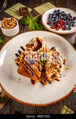 Crêpes avec crème au chocolat décoré avec du sirop de chocolat et noix Banque D'Images