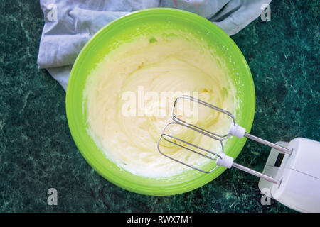 Le processus de cuisson gâteau napoléon, mixer dans un bol de crème de fouets sur une table de marbre vert, vue du dessus. Recette Dessert. Banque D'Images