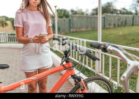 Girl détient la main de téléphone mobile, photos gratuit location. En été, l'application de la ville en ligne, Internet poster dans les réseaux sociaux. Vélo Concept perdre Banque D'Images