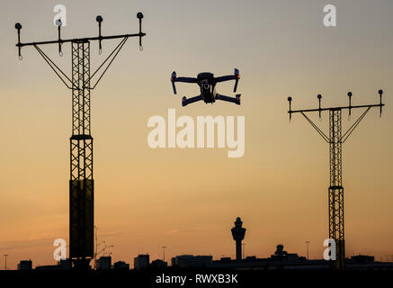 Drone sans pilote volant près de piste à l'aéroport en approchant de la piste entre l'éclairage au coucher du soleil. Banque D'Images