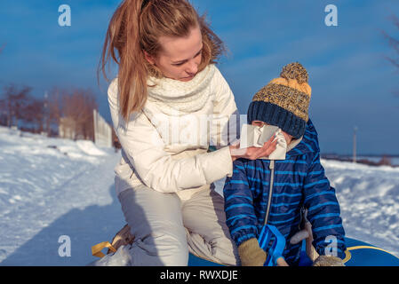 Une jeune mère essuie son nez avec un mouchoir, une serviette, de morve, un petit garçon est un fils de 3 à 6 ans. En hiver, la nature, l'écoulement de la toux. Malade, froid Banque D'Images