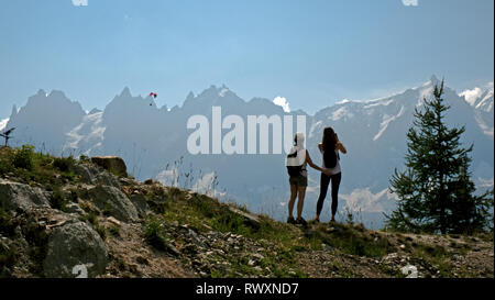 Les femelles les randonneurs de profiter de la vue sur les montagnes et les planeurs para sur la vallée de Chamonix, en France et en direction du Mont Blanc dans les Alpes françaises. Banque D'Images