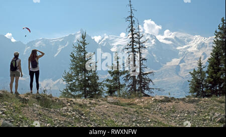 Les femelles les randonneurs de profiter de la vue sur les montagnes et les planeurs para sur la vallée de Chamonix, en France et en direction du Mont Blanc dans les Alpes françaises. Banque D'Images