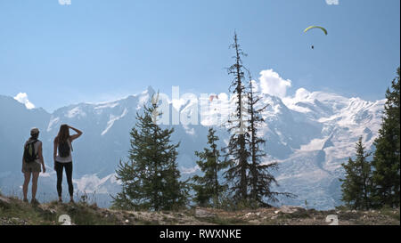 Les femelles les randonneurs de profiter de la vue sur les montagnes et les planeurs para sur la vallée de Chamonix, en France et en direction du Mont Blanc dans les Alpes françaises. Banque D'Images