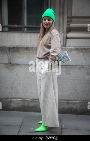 LONDON - 15 février 2019 : les participants à l'extérieur rassemblement élégant 180 The Strand pour la Semaine de la mode de Londres. Jeune fille dans un tailleur-pantalon gris pantalon à rayures larges, en Banque D'Images