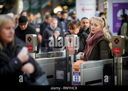 La gare Victoria de Manchester Scène mouvementée comme exécuter heure de passagers transitent par le système automatisé de barrières de billets Banque D'Images