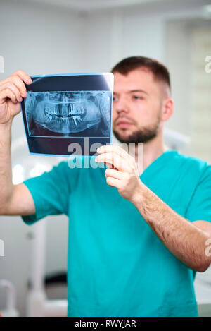 Homme de race blanche dentiste holding x en mains et souriant. À la recherche vers la caméra Banque D'Images