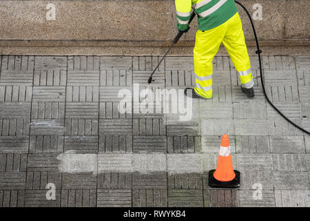 Nettoyage du trottoir de la rue le travailleur avec jet d'eau à haute pression. Concept d'entretien public Banque D'Images