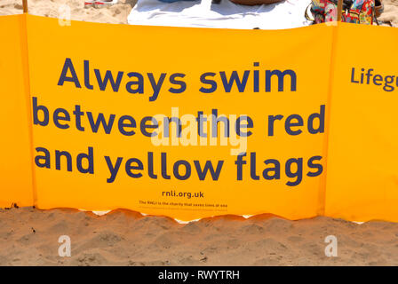 Bannière RNLI sur beach conseiller ' toujours nager entre les drapeaux rouge et jaune', Port Eynon, au Pays de Galles Banque D'Images