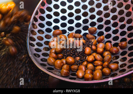 Torréfaction châtaignes avec galets noirs. L'alimentation de rue asiatique traditionnel cuit dans Yaowarat Road ou China town, Bangkok, Thaïlande Banque D'Images