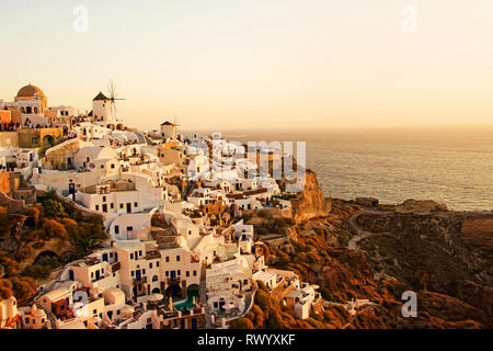 Beau paysage classique avec des bâtiments blancs vintage et moulins à vent à Oia sur l'île de Santorin, Grèce au coucher du soleil Banque D'Images