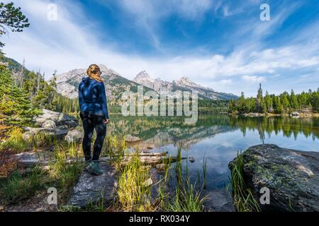 Jeune femme debout à un lac, reflet dans le lac Taggart, vue sur les montagnes de Teton Range, Grand Teton National Park Banque D'Images