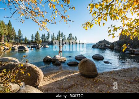 Young woman in bikini debout sur une pierre ronde dans l'eau, Bay au lac Lake Tahoe, parc d'État Sand Harbor, Port, Californie Banque D'Images