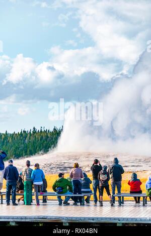 Les touristes observer éruption de l'Old Faithful Geyser, Yellowstone National Park, Wyoming, USA Banque D'Images