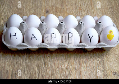 Concept d'oeufs de poules heureux avec oeufs blancs dans une boîte avec le mot heureux écrit sur les oeufs Banque D'Images