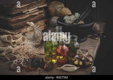 Bouteilles d'huile essentielle, de mortier mousse séchée, de vieux livres, des racines et des plantes sèches. La médecine de fines herbes. Banque D'Images