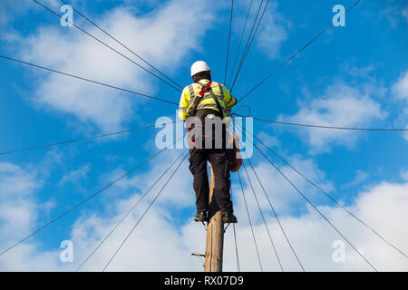 Telecom ingénieur travaillant sur la ligne de téléphone internet haut débit / d'un fil de cuivre téléphone / poteau télégraphique dans une rue de Londres / Road, et ciel bleu Banque D'Images