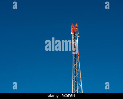 4G ou GSM antenne sur un téléphone mobile rouge et blanc mât contre un ciel bleu Banque D'Images