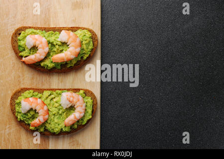 Crevettes et guacamole avec du pain sur dark retour Banque D'Images