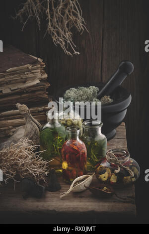 Bouteilles d'huile essentielle, de mortier mousse séchée, de vieux livres, des racines sèches, les noix et les plantes. La médecine de fines herbes. Banque D'Images