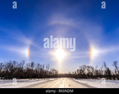 Les Sundogs et Halo solaire, sur une route rurale, Manitoba, Canada Banque D'Images