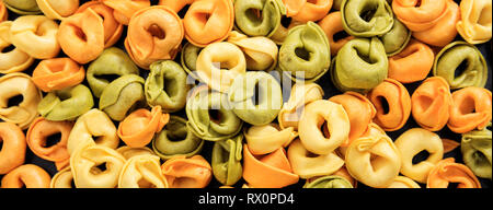 Cuisine italienne. Les pâtes non cuites coloré sec tortellini texture background, bannière Banque D'Images