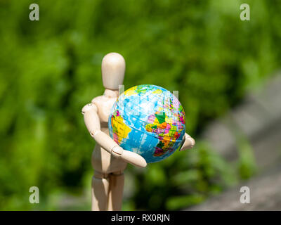 Un mannequin en bois avec un ballon dans ses bras. Concept de l'écologie, la mondialisation Banque D'Images