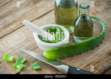 Feuille d'aloe vera, mortier blanc haché plein de l'aloès et bouteilles de gel d'aloès ou l'infusion. Banque D'Images