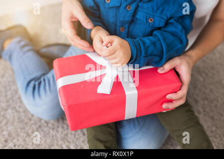 Les enfants, anniversaire et maison de vacances - petit enfant garçon rouge d'ouverture fort avec présent Banque D'Images