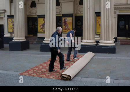 Les monteurs de tapis déroulez une nouvelle moquette dans la rue pour l'intérieur du Lyceum Theatre, sur la rue Wellington, le 5 mars 2019, à Londres, en Angleterre. Banque D'Images