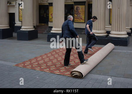 Les monteurs de tapis déroulez une nouvelle moquette dans la rue pour l'intérieur du Lyceum Theatre, sur la rue Wellington, le 5 mars 2019, à Londres, en Angleterre. Banque D'Images