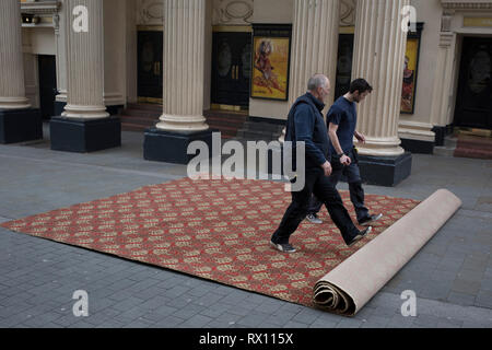 Les monteurs de tapis déroulez une nouvelle moquette dans la rue pour l'intérieur du Lyceum Theatre, sur la rue Wellington, le 5 mars 2019, à Londres, en Angleterre. Banque D'Images