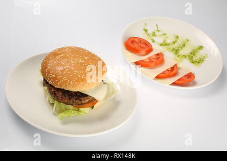 Cheeseburger avec escalope de boeuf, bacon, tomates et tranches de fromage, assaisonné de sauce et salade verte pour un menu de restaurant sur une zone isolée blanc Banque D'Images