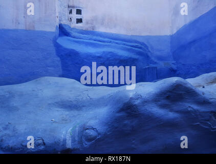 Fond bleu mur de pierre, blanc sur le haut avec des courbes lisses avec une petite fenêtre au milieu, Médina de Chefchaouen, Maroc. Banque D'Images