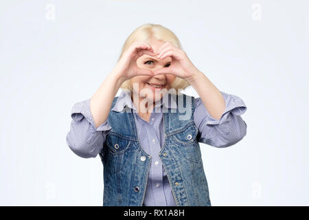 L'amour, forme de cœur, la paix. Smiling blonde femme, fille révèle coeur signer avec l'aide de ses mains Banque D'Images