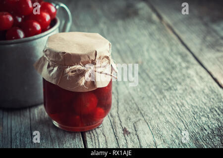 Pot de confiture de cerise et tasse de cerises mûres pas dans l'accent sur table en bois. L'espace de copie pour le texte. Banque D'Images