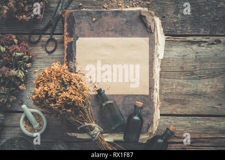 Bouteilles teinture, assortiment de plantes saines à sec, de vieux livres, mortier, des ciseaux. La médecine de fines herbes. De style rétro. Haut de la vue, télévision lay. Banque D'Images