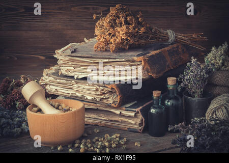 Bouteilles teinture, grappes de sécher les herbes en bonne santé, de la pile de livres anciens, mortiers, sac d'herbes médicinales. La médecine de fines herbes. Banque D'Images