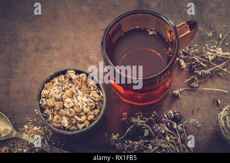 Tasse de thé en bonne santé, de mortier rustique daisy herbes, thym séché sur la table. La médecine de fines herbes. Banque D'Images