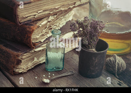Pile de livres anciens, vintage de mortier des herbes médicinales, des globules homéopathiques flacon de teinture et de bouteille. Banque D'Images