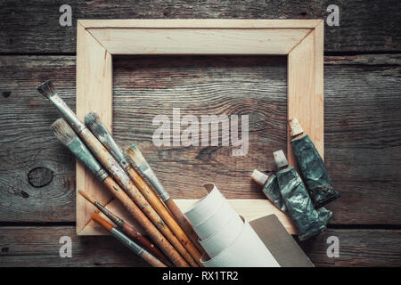 La barre de civière en bois, pinceaux, rouleau de toile de l'artiste tubes de peinture et sur l'ancien fond de bois. Vue d'en haut. L'espace de copie pour le texte. Banque D'Images