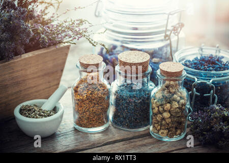 Bouteilles et pots d'herbes curatives, mortier et boîte en bois de fleurs sèches, la médecine de fines herbes. Banque D'Images