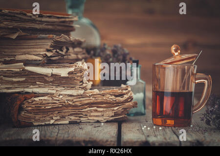 Livres Anciens, teinture ou de thé en bonne santé dans le verre, flacon de globules homéopathiques et de plantes médicinales. Banque D'Images