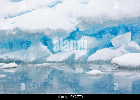 Un iceberg est lentement recouvert de neige d'une tempête d'été près de l'Île Pleneau, Pleneau Island, péninsule antarctique, Canal Lemaire Banque D'Images