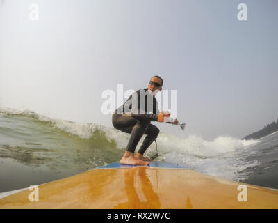 Paddle homme surfer est une vague dans l'océan Pacifique. Prises à Tofino, Vancouver Island, British Columbia, Canada. Banque D'Images