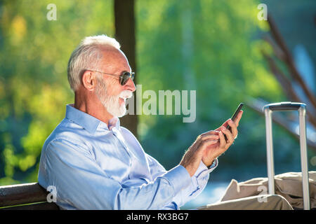Senior homme barbu message entrant dans le parc. Banque D'Images