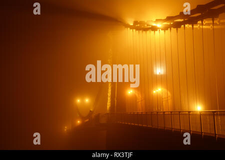 Misty brumeux et pont suspendu de Menai de nuit. Ce pont relie le continent gallois avec la magnifique île d'Anglesey. Banque D'Images