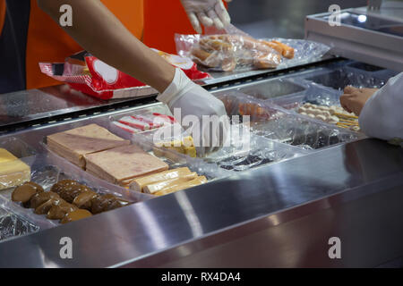 Travailleur mettre de la nourriture dans le bac en plastique pour l'emballage de la machine à Banque D'Images